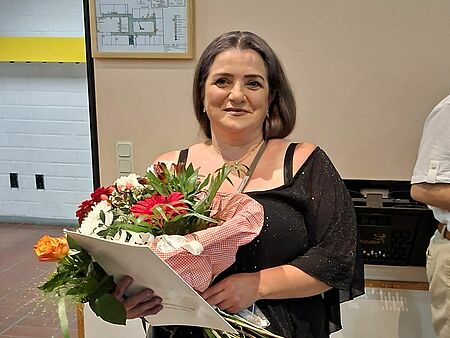 Das Bild zeigt unsere Mitarbeiterin Natavan Mukhtarova mit einem Blumenstrauß.